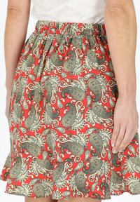Gonna rossa a motivi paisley con una vita elastica, caratterizzata da intricati motivi crema e neri. Tessuto leggero con un design fluente.