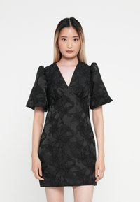 Čierne mini šaty s kvetinovou textúrou, hlbokým v�ýstrihom do V, nariasenými rukávmi a priliehavým strihom. Hladká tkanina s intricate vzorom.