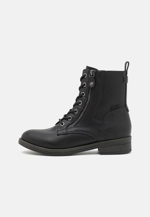 Botín negro de tobillo hecho de cuero texturizado, con cremallera frontal, diseño de cordones, punta redonda y un tacón bajo.