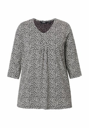 Zwarte en witte tuniek met een V-hals, driekwart mouwen, plooien aan de voorkant en een bladvormig patroon door het geheel. Glad stofoppervlak.
