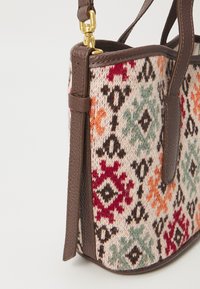 Borsa a tracolla in arazzo tessuto con motivi multicolori, caratterizzata da rifiniture in pelle marrone e una tracolla con accenti in metallo dorato.