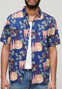 Korte mouwen shirt in marineblauw met een bloemen- en lantaarnpatroon. Heeft knopen, een kraag en een ontspannen pasvorm. Gemaakt van lichtgewicht stof.