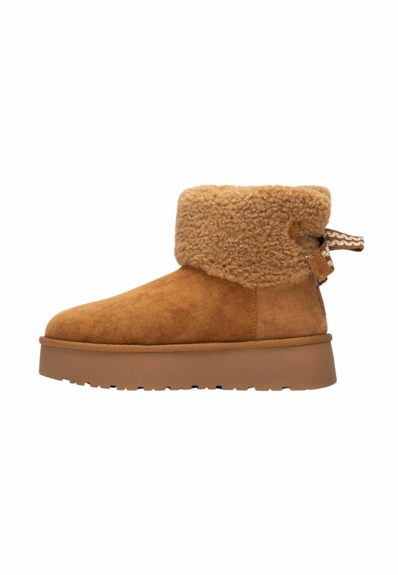 Stivaletti alla caviglia in suede marrone con un colletto in pelliccia sintetica beige e soffice. I dettagli includono un occhiello e una suola in gomma spessa con un motivo testurizzato.