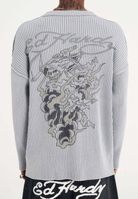 Grey ribbed sweater featuring a graphic design of skulls and smoke on the back. Long sleeves with a relaxed fit.
