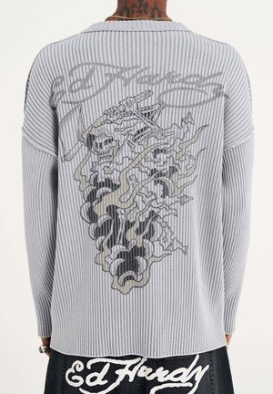 Grauer gerippter Pullover mit einem Grafikdesign von Schädeln und Rauch auf dem Rücken. Lange Ärmel mit einem lässigen Schnitt.