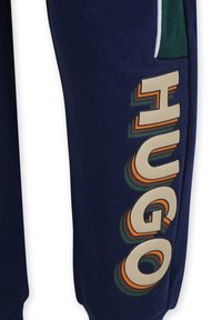 Marineblauwe joggers met een groot, kleurrijk "HUGO" logo aan de zijkant, met een zachte textuur en een groene accentzak.