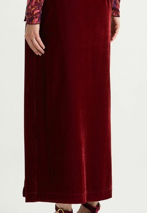 Long, burgundy velvet skirt with a smooth texture and subtle shine. Features a straight cut and hem with neat stitching details.