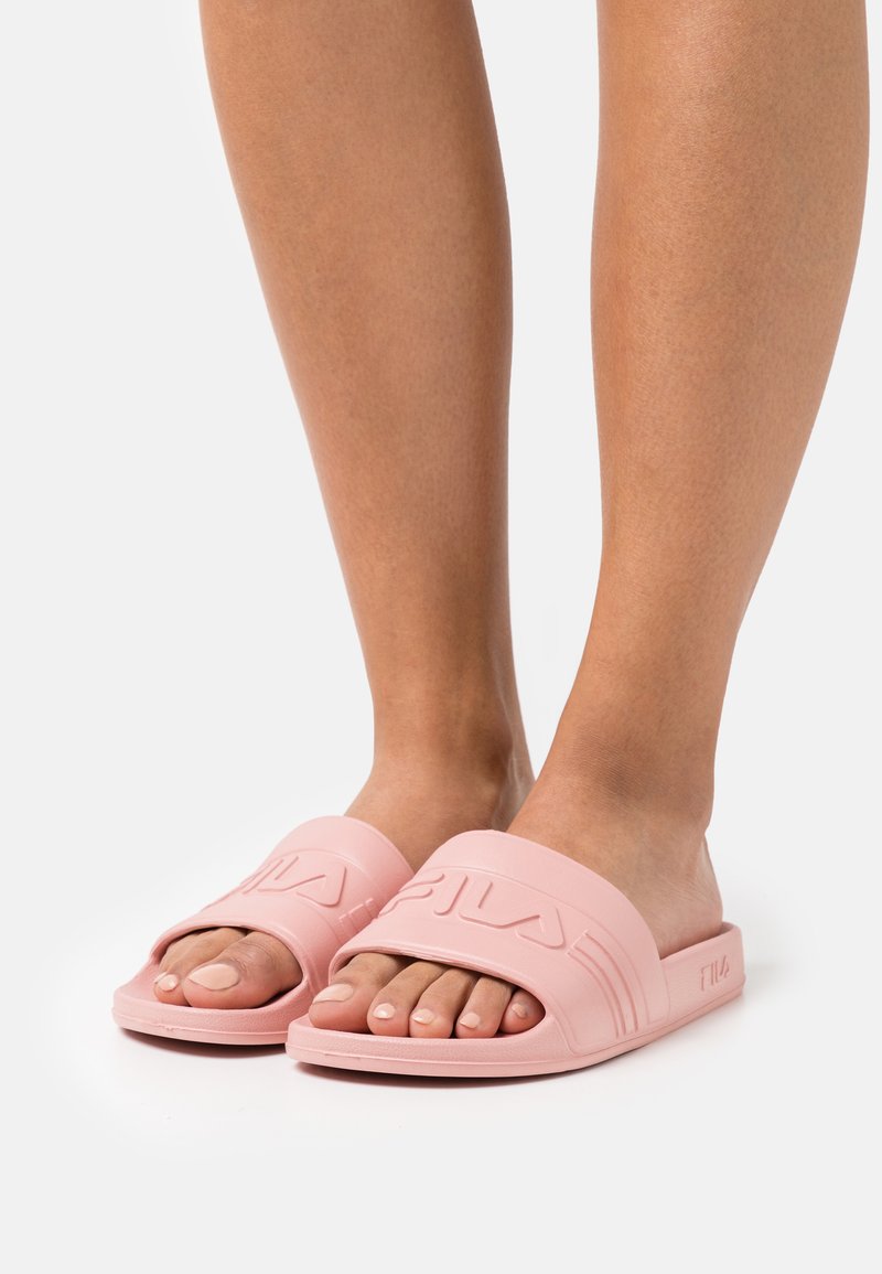 Infradito di gomma rosa con una fascia larga con logo in rilievo, design open-toe e suola piatta. La superficie è liscia e opaca.
