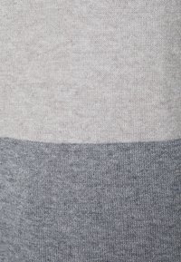Tessuto di maglione lavorato a maglia con due sezioni orizzontali: grigio chiaro in alto e grigio scuro in basso, con una consistenza morbida e una fine costina.