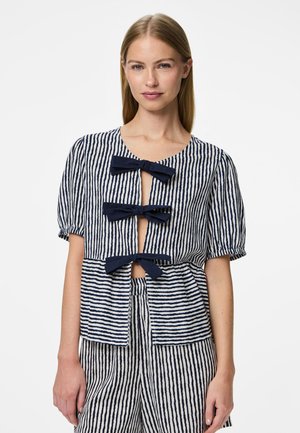 Top a righe in blu navy e bianco, con maniche a sbuffo corte, scollo rotondo e tre decorazioni a fiocco sul davanti. Materiale in cotone leggero.