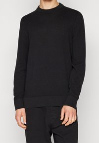 Černý pletený svetr s kulatým výstřihem, dlouhými rukávy a texturovaným vzorem. Dokončený žebrovanými manžetami a spodním lemem.