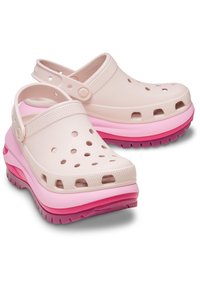 Zuecos de color rosa claro con agujeros de ventilación y correas ajustables, que presentan suelas gruesas en tonos de rosa y morado.