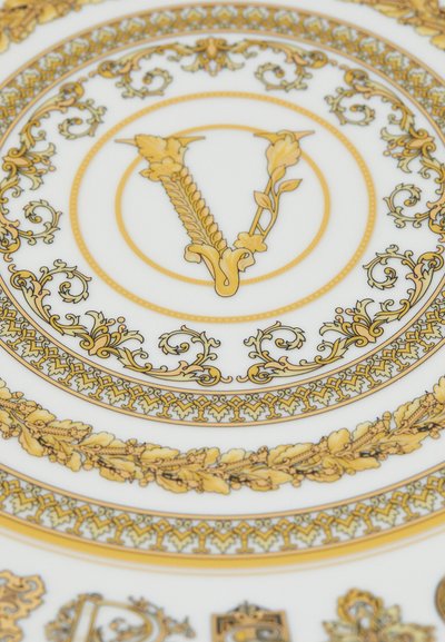 Dekoracyjny porcelanowy talerz z misternymi wzorami z liści złota, kwiatowymi akcentami oraz centralnym emblematem ze stylizowaną literą "V" na białym tle.