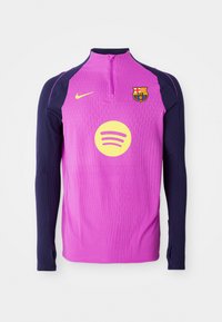 Lilla langærmet træningstop med marineblå ærmer, lynlås i halsen, ribbet tekstur, Barcelona klubmærke og cirkulært gult Spotify-logo.