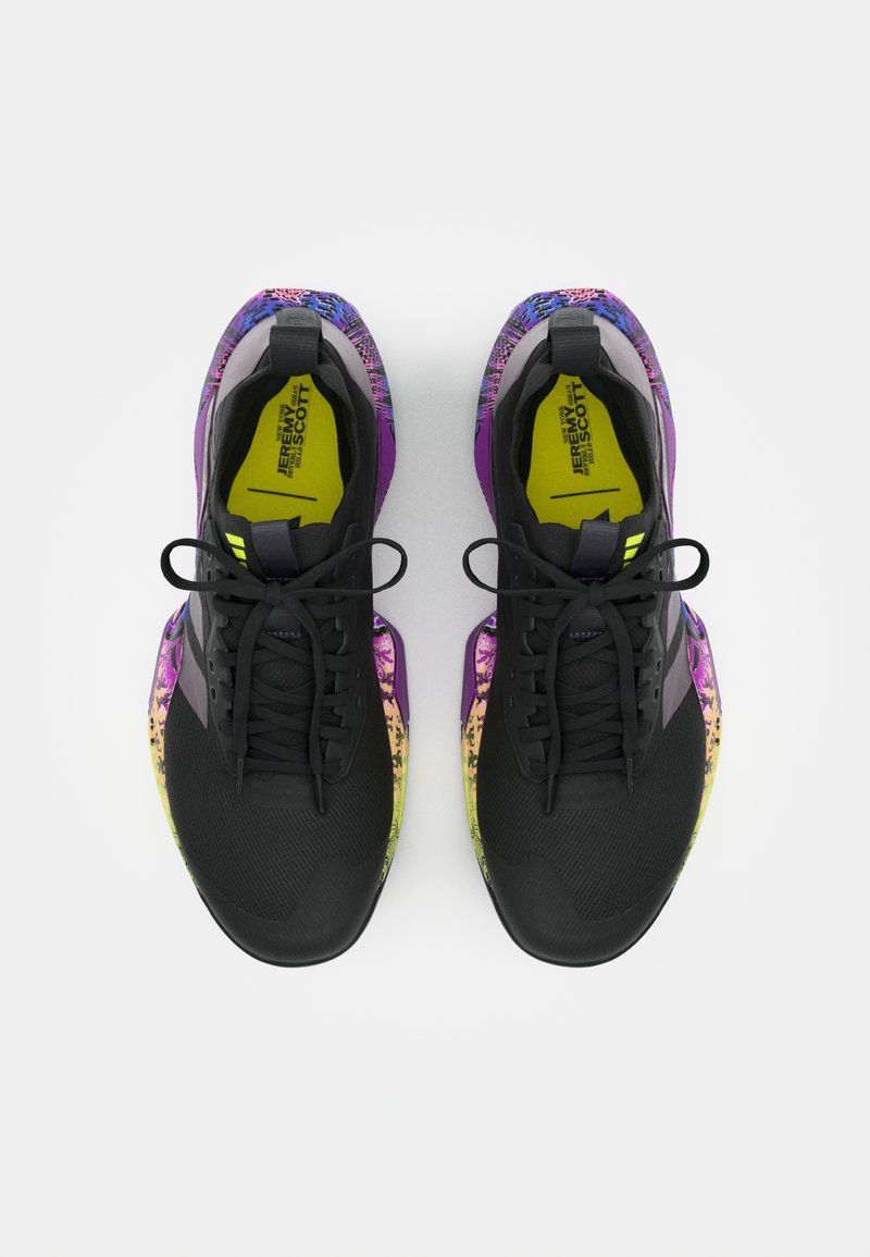 Zapatillas deportivas negras con un exterior texturizado, que presentan un diseño gráfico colorido que transita del púrpura al amarillo en la suela.