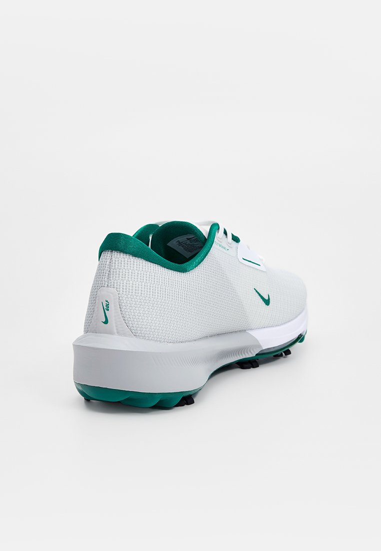Chaussure de sport grise et blanche avec des accents verts, présentant un dessus en maille texturée et une semelle rembourrée conçue pour l'adhérence et le confort.