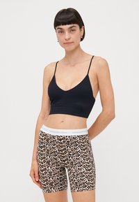 Svart sømløs sports-BH med tynne stropper, kombinert med sykkelshorts i leopardmønster med en hvit midje med teksten "Copenhagen Studios".