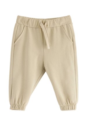 Beige barnbyxor med elastisk midja, dragsko, sidofickor och elastiska muddar på vit bakgrund.