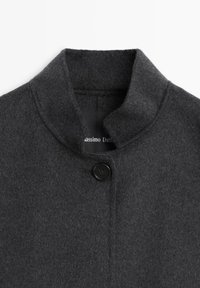 Cappotto di lana grigio scuro con colletto arrotondato, chiusura con un pulsante nero singolo e una texture liscia. Etichetta con la scritta "Massimo Dutti".