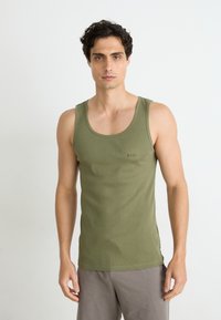 Olivgrünes, geripptes Tanktop mit Rundhalsausschnitt und dem BOSS-Logo auf der Vorderseite, ergänzt durch graue Shorts und natürliche Hauttextur.