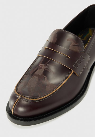 Bruine leren loafers met een gladde afwerking en een decoratief reliëfpatroon. Voorzien van een goudkleurige accentband en contrasterende stiksels.