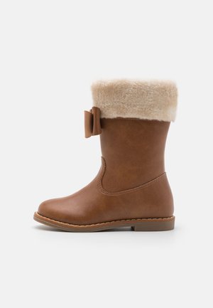 Braune Stiefeletten aus Kunstleder mit einem cremefarbenen Kunstfellbund und einem seitlichen Schleifchen. Abgerundete Zehenform und flache Sohle mit stickaccentuierungen.