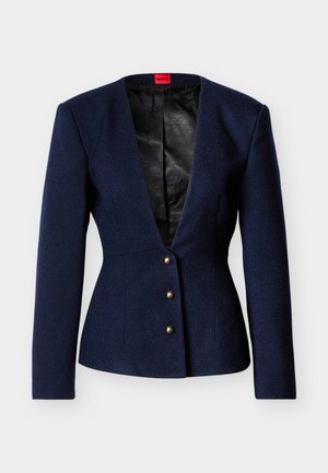 Μπλε σκούρο υφασμάτινο σακάκι με μακριά μανίκια, βαθύ V-λαιμόκοψη και τρία χρυσά κουμπιά. Εσωτερικά επενδυμένο με μαύρο ύφασμα με γεωμετρικό σχέδιο.