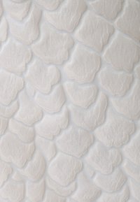 Textured fabric featuring overlapping, scale-like shapes in a soft white color. Smooth surface with delicate stitching outlining each shape.