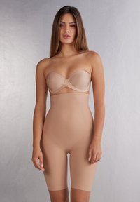 Nude naadloze vormgevende body met een strapless ontwerp, lengte tot halverwege de bovenbenen en glad, rekbaar materiaal voor het accentueren van de contouren.