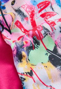 Barvit tekstil z mešanico vzorcev v živahnih odtenkih roza, zelene in rdeče ter gladko teksturo. Vsebuje tudi enobarven roza del.