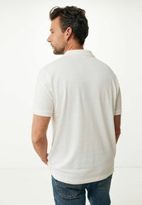 Witte polo met korte mouwen en subtiele horizontale strepen, voorzien van een klassieke kraag en een casual pasvorm, gecombineerd met blauwe jeans.