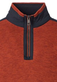 Rood textuurpullover met een marineblauwe kraag en een half-rits aan de voorkant. Heeft een geribbeld breipatroon en contrasterende kleuraccenten.