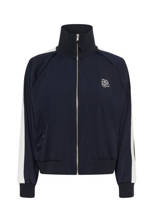 Marineblauwe ritsjack met hoge kraag, witte zijpanelen en geborduurd logo. Voorzien van elastische manchetten en voorzakken. Gladde stoftextuur.