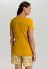 Korte mouwen gele T-shirt van zacht materiaal, met een ronde hals. Gecombineerd met gestreepte shorts in wit en geel.