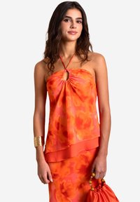 Bodenloses orangefarbenes Blumenshirt mit einem gerafften Schlüssel-Ausschnitt, geschichtetem Design und leichtem Stoff; kombiniert mit einem passenden Rock und goldenen Accessoires.