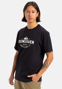 Camiseta de algodón negra con un logo y texto de Quiksilver en blanco. Corte clásico con mangas cortas y cuello redondo.