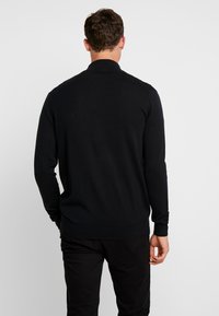 Czarny sweter rozpinany z dzianiny, z prążkowanym dołem i mankietami. Charakteryzuje się gładką teksturą i długimi rękawami, zaprojektowany bez widocznych logo ani wzorów.