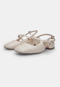 Decolletées slingback in pelle patent lucida color nude, con punta affusolata, design a strap incrociato e tacco basso a blocco.