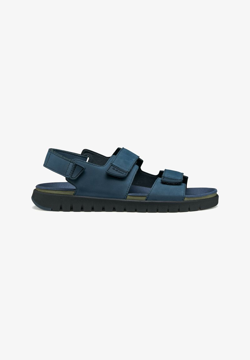 Sandale bleu marine à bout ouvert avec brides réglables en Velcro, semelle intérieure rembourrée et semelle extérieure en caoutchouc texturé noir pour une utilisation en extérieur.