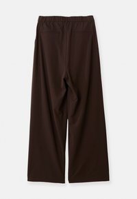 Pantalons larges marron foncé avec taille élastique et deux poches passepoilées au dos, posés à plat vu de l'arrière sur fond blanc.
