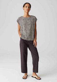Zwart-wit gestreepte kortekorte top gecombineerd met donkere, losse broek en lichte slippers. Zachte textuur, relaxte pasvorm, minimaal ontwerp.