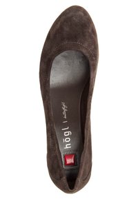 Chaussure plate en suède marron avec un bout rond, comprenant une doublure intérieure lisse et un accent carré rouge près du talon. Logo imprimé à l'intérieur.