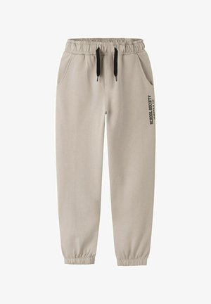 Pantalons de jogging beiges avec une taille élastique, cordon de serrage noir ajustable, poches latérales, et un logo imprimé sur la jambe gauche avant.