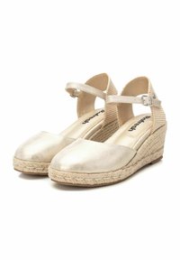Zapatos de tacón en color beige con parte superior de piel metálica, media suela envuelta en yute y correas para el tobillo. Presentan un acabado suave y un diseño de punta redonda.
