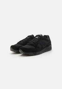 Sneakers neri realizzati con una combinazione di materiali scamosciati e mesh. Punta arrotondata, design con lacci piatti e suola in gomma testurizzata con motivi di aderenza.