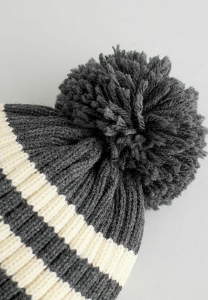 Berretto lavorato a maglia con righe orizzontali grigio scuro e bianche, decorato con un pompon tondo e soffice grigio scuro. Tessuto morbido e texture.