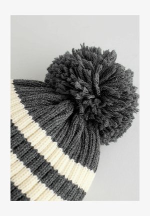 Gorro de punto con rayas horizontales en gris oscuro y blanco, rematado con un pompón redondo y esponjoso en gris oscuro. Tejido suave y texturizado.