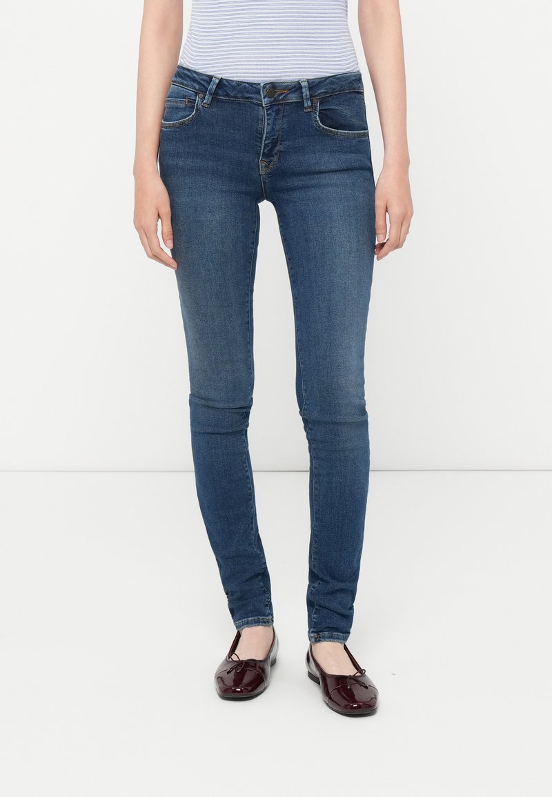 Λεπτά μπλε τζιν από ντένιμ με λεία υφή, χαρακτηριστικά με κλασικό σχέδιο πέντε τσεπών και φερμουάρ με κλείσιμο κουμπιού.