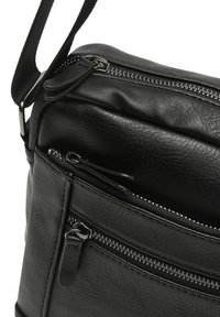 Borsa a spalla in pelle nera con più scomparti con zip, una texture liscia e una tracolla removibile. Presenta hardware in tonalità argento.