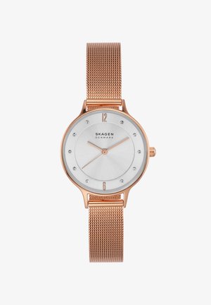 Reloj de pulsera Skagen en oro rosa con correa de malla, esfera blanca, marcadores mínimos y agujas finas que muestran las 1:43:38.